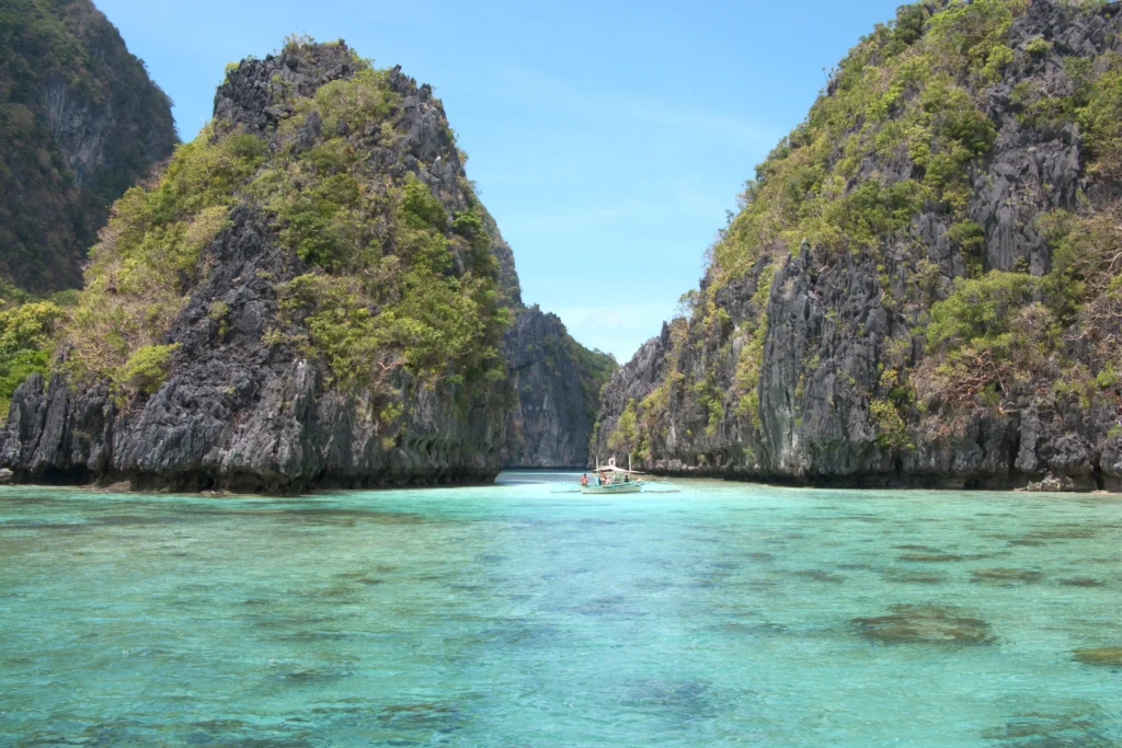 A sheltered island lagoon ringed by limestone karst in Bacuit Bay, El Nido.