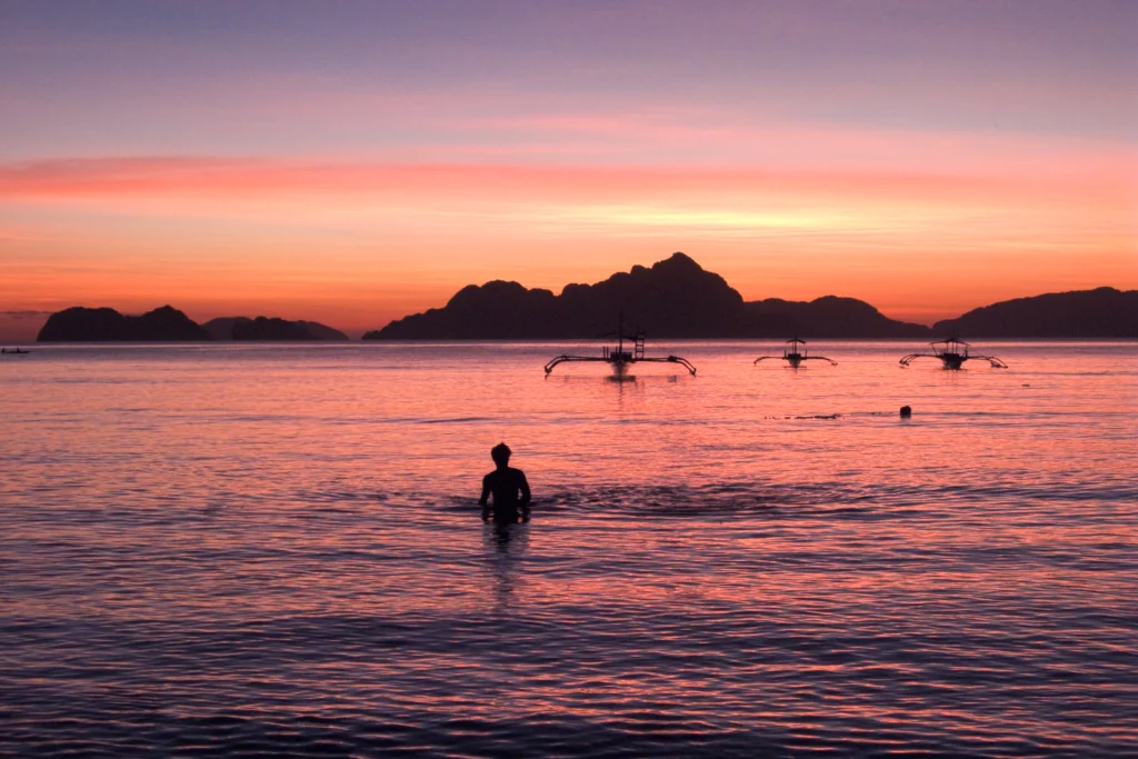 Sunset over the water and outrigger boats at El Nido, Palawan.