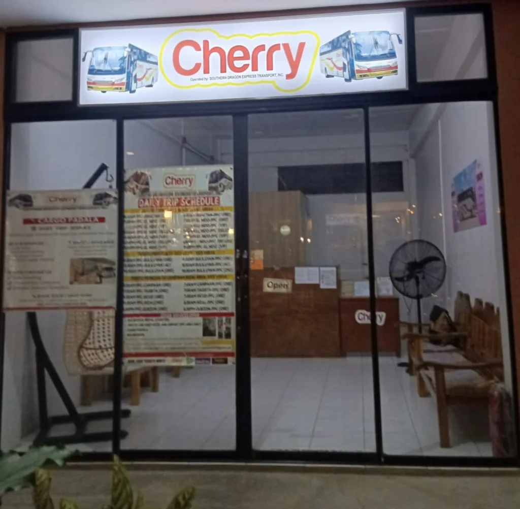 The Cherry ticket office in Puerto Princesa in the evening, with the Cargo Padala and daily trip schedule posters in the window.