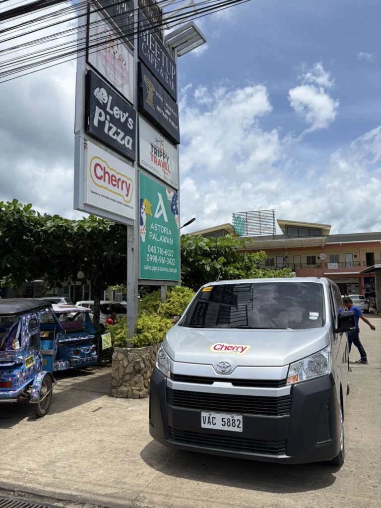 The Cherry sign on the roadside pylon in Puerto Princesa, with a Cherry transfer van parked beneath it.